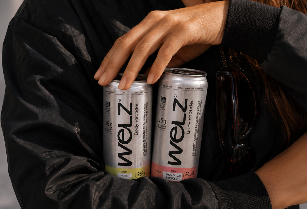 Mulher de jaqueta preta segurando duas latas de Welz Body Peptides nos sabores yuzu e limonada com framboesa